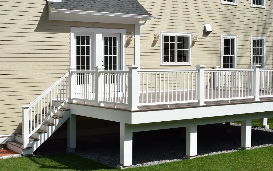 Elevated composite deck with a white railing and stairs behind an Orlando home