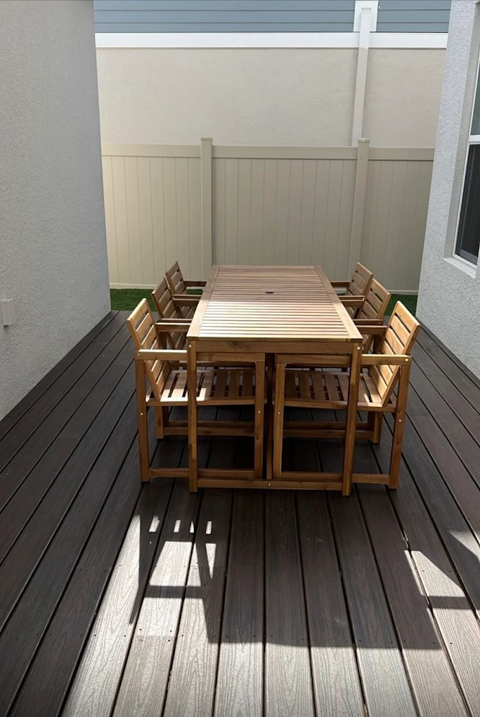 Espresso composite deck with an outdoor dining set and vinyl privacy fence